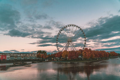 Ferris wheel by river against sky