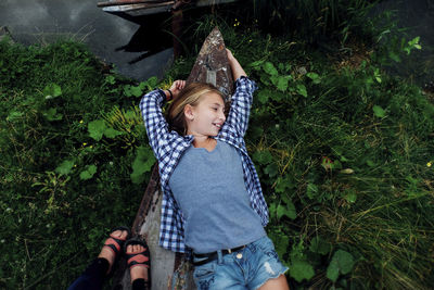 Overhead view of teenage girl lying on ship's bow at lakeshore