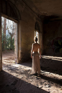 Rear view of woman standing in abandoned building