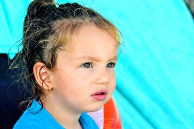 Close-up of girl looking away against turquoise towel