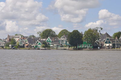 Houses by trees and buildings against sky