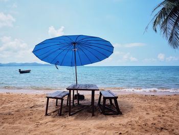 Deck chairs on beach against sky