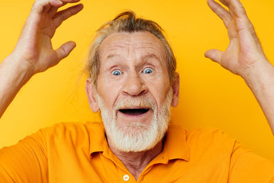 Portrait of senior man against yellow background