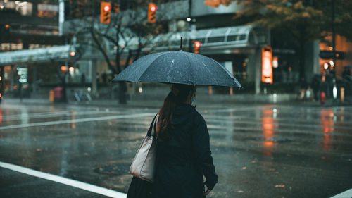 Woman walking on wet road during rainy season