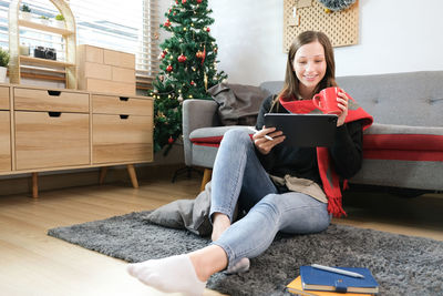 Low section of woman using laptop while sitting on sofa at home