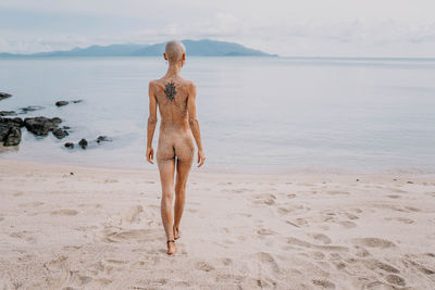 Rear view of woman standing at beach