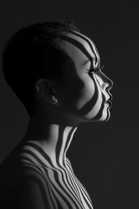 Side view of topless thoughtful young woman against black background