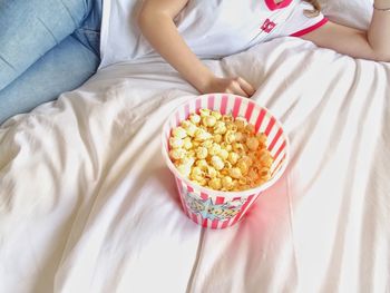 High angle view of woman holding popcorn on bed