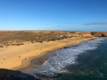 Scenic view of sand dunes against clear blue sky