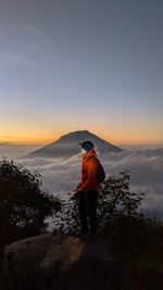 Man standing on mountain against sky during sunset