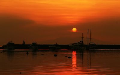 Silhouette boats in sea against orange sky