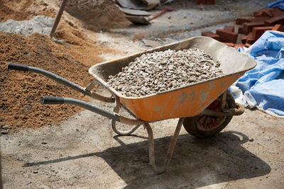 Wheel barrow of building material sand rock and cement for construction