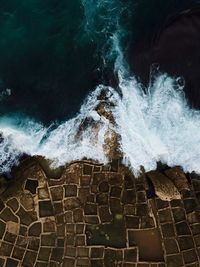High angle view of sea waves splashing on rocks