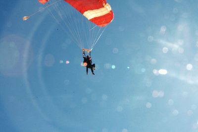 Low angle view of man paragliding against sky