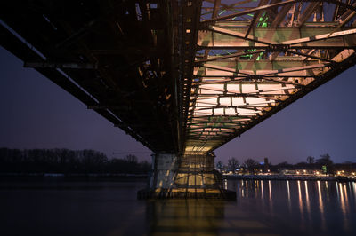 Illuminated bridge over river against sky at night