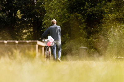 Rear view of person walking with bicycle on road