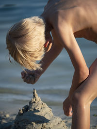 Cute boy making sandcastle at lakeshore