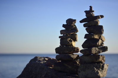 Stack of stones on sea shore against clear sky