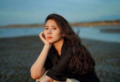 Portrait of beautiful young woman at beach against sky