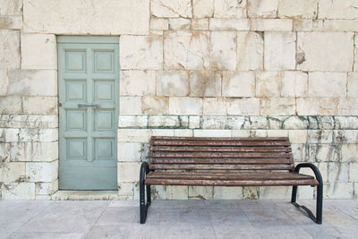 Empty bench against wall of old building