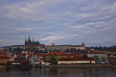 View of buildings at waterfront against cloudy sky