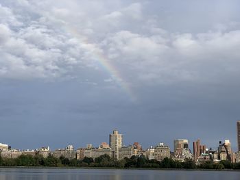 Rainbow over buildings in city against sky