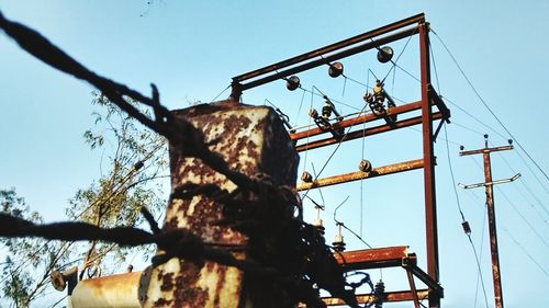 Barbed wire tied on rusty metal post at electricity substation