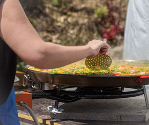 Midsection of woman preparing food on stove burner outdoors