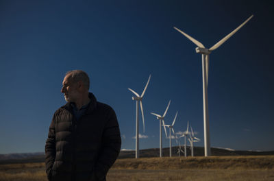 Adult man in land with modern windmills in background against blue sky. castilla la mancha, spain