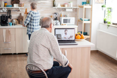 Rear view of man talking on video call at home