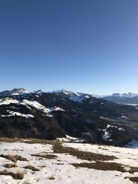 Scenic view of snowcapped mountains against clear blue sky