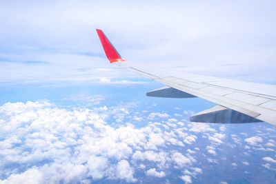 Airplane wing over clouds against sky