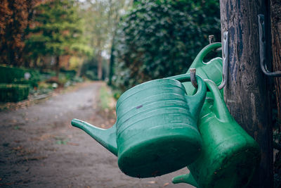 Close-up of green watering cans in park