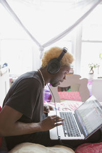 A young man wearing headphones with a laptop