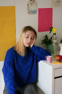 Young woman with eyes closed sitting by table at home