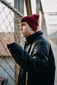 Portrait of young man looking away, standing in a bridge.