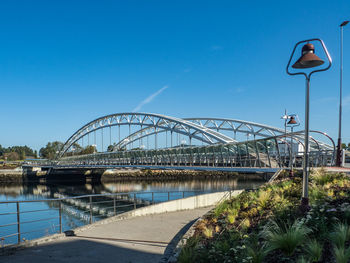 Bridge over river against clear blue sky