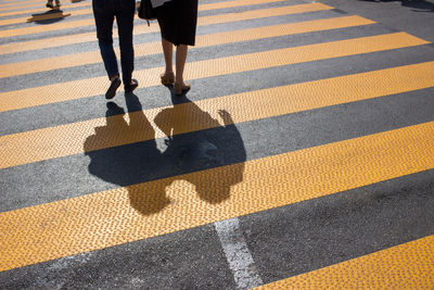 Low section of people walking on zebra crossing