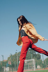 Low angle view of woman jumping on soccer field