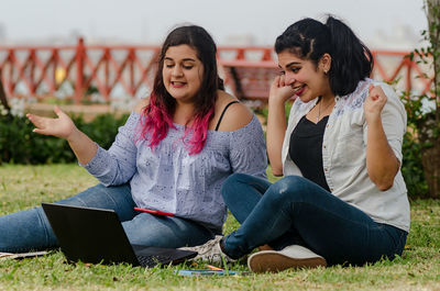 Cheerful friends using technology at park