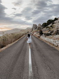 Rear view of woman standing on road against sky