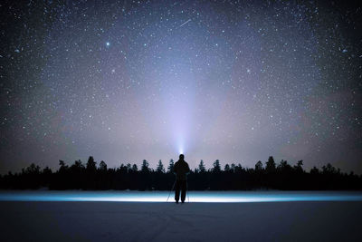 Rear view of silhouette woman standing against sky at night