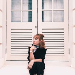 Young woman standing against window