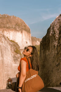 Young woman wearing sunglasses on rock at mountain