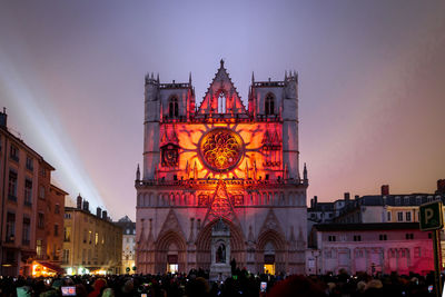 People in illuminated building against sky at dusk