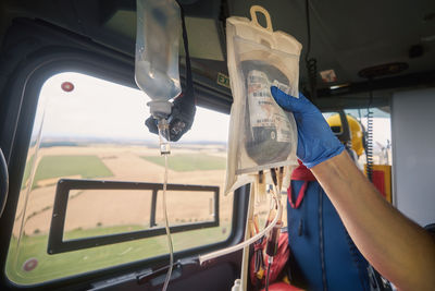 Hand of doctor holding transfusion bag with blood on board helicopter of emergency medical service.
