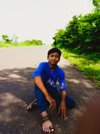 Portrait of smiling young woman sitting on road