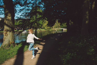 Boy running on road amidst trees