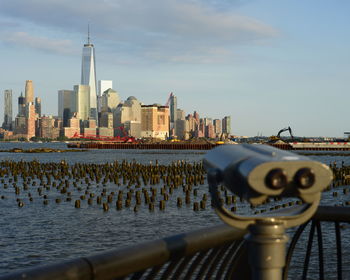 Close-up of coin-operated binoculars with buildings in backgrounds