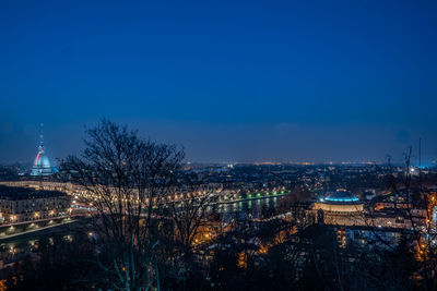 Aerial view of illuminated buildings against blue sky at night